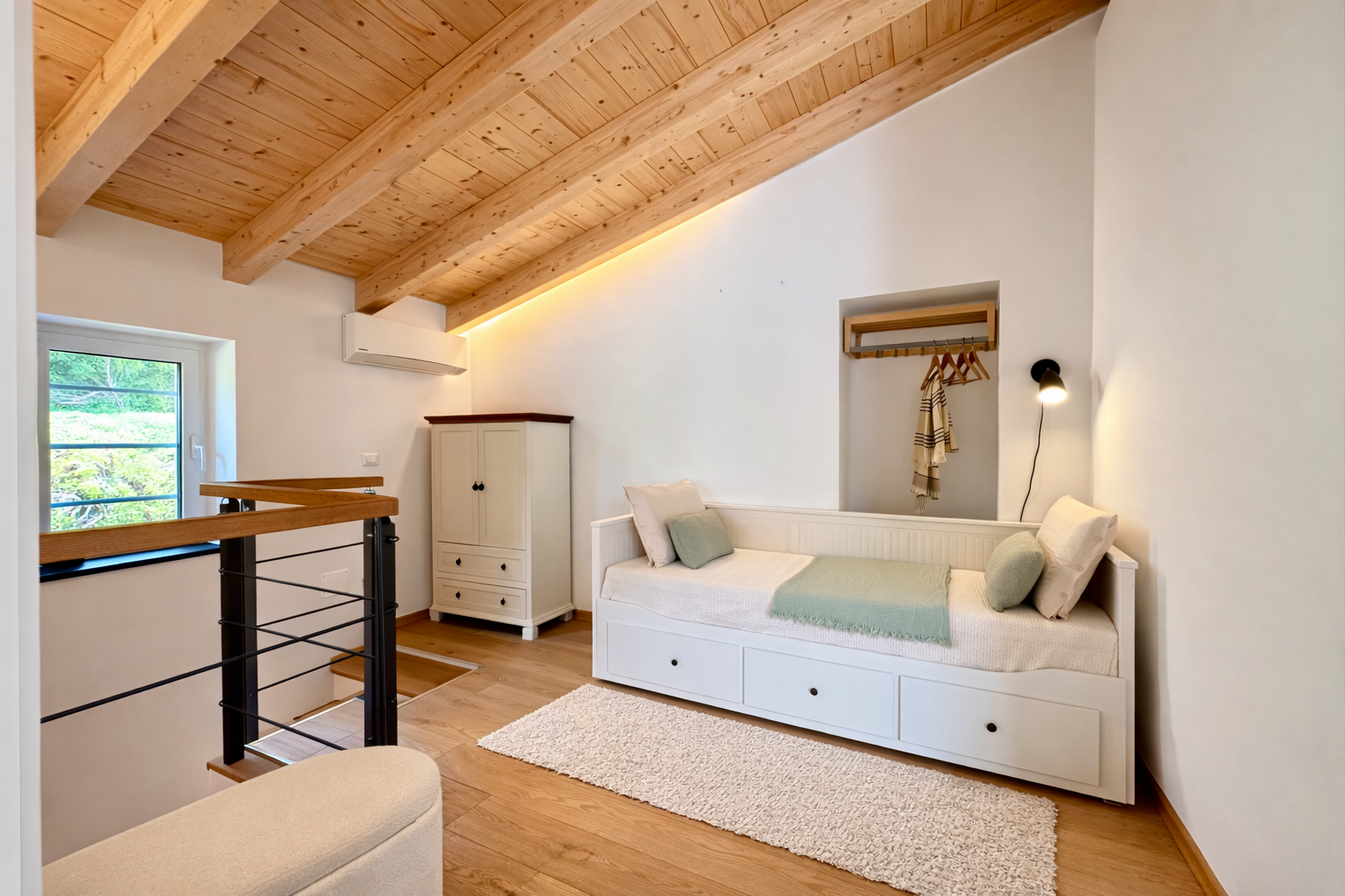 Upstairs gallery with single bed, wooden ceiling and wardrobe